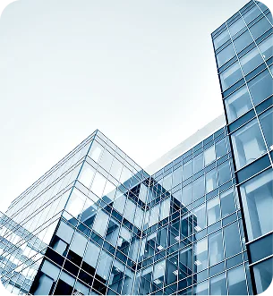 Low-angle view of glass office buildings reflecting the sky and clouds.