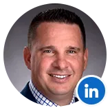Professional headshot of a smiling man in a navy suit, suitable for a LinkedIn profile.