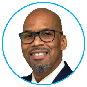 Portrait of a smiling bald man wearing glasses and a dark suit, against a white background in a circular blue-framed image.